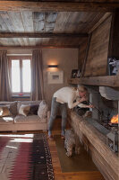 Offener Kamin an holzverkleideter Wand mit rustikalem Holzbalken als