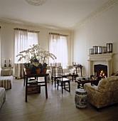 A collection of orchids in full bloom cover a table in this drawing room which is furnished with a selection of antique Chinese chairs, benches and tables