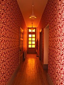 Schmaler Flur mit rot weissem Ornamentmuster auf Tapete an Wand