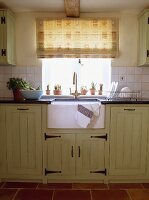 Gemustertes Raffrollo über dem weissen Spülbecken aus Keramik in einer