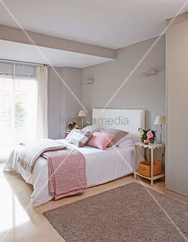 Double bed with blankets and scatter cushions in pastel grey and ...