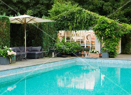 Türkisfarbener Pool mit Sonnenschirm über Polstersitzgruppe; dicht