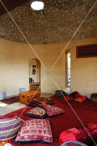 Bunte, indische Kissen auf rotem Teppich in Meditationsraum mit ...