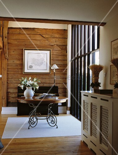 Runder Holztisch mit geschwungenen Metallfüssen vor holzverschalter