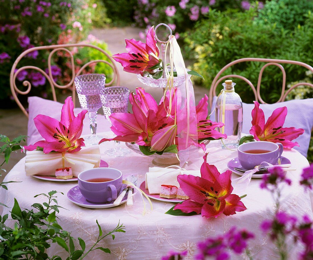 Tisch mit Teegedeck und Lilien im Freien
