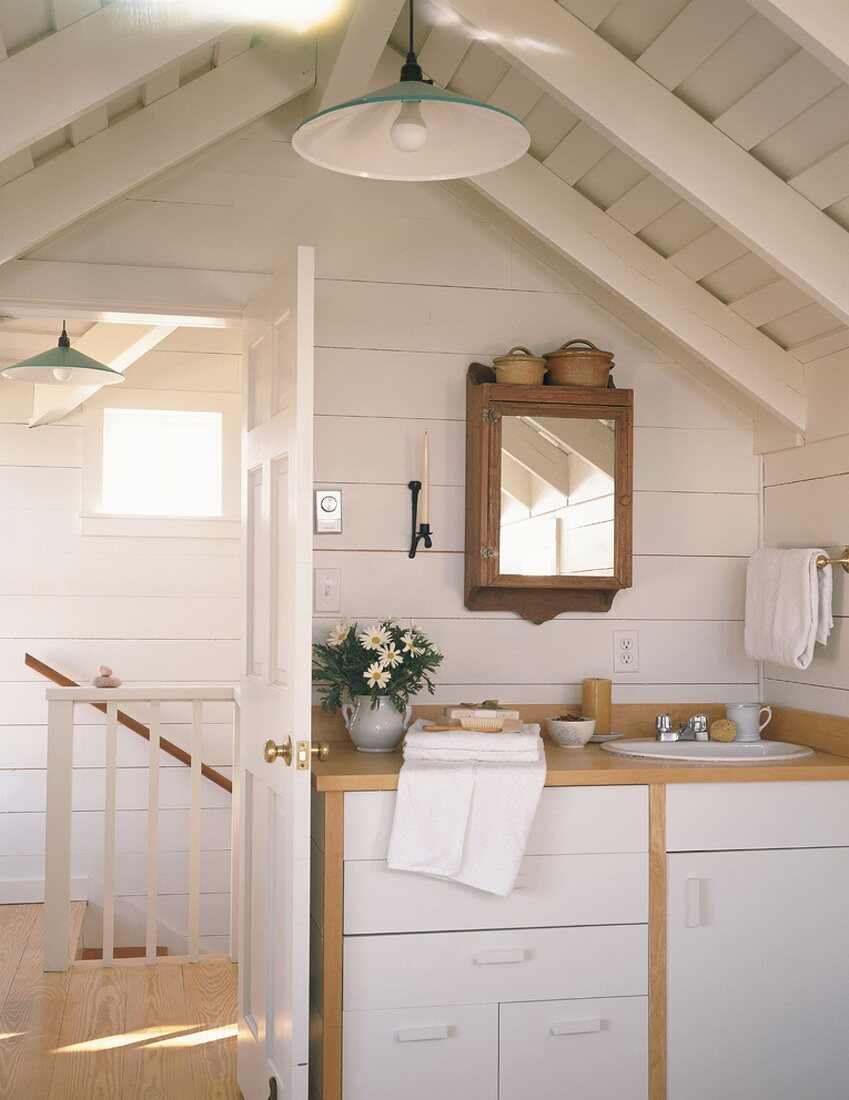 Waschbecken und Spiegel in einem Badezimmer mit Dachschrägen