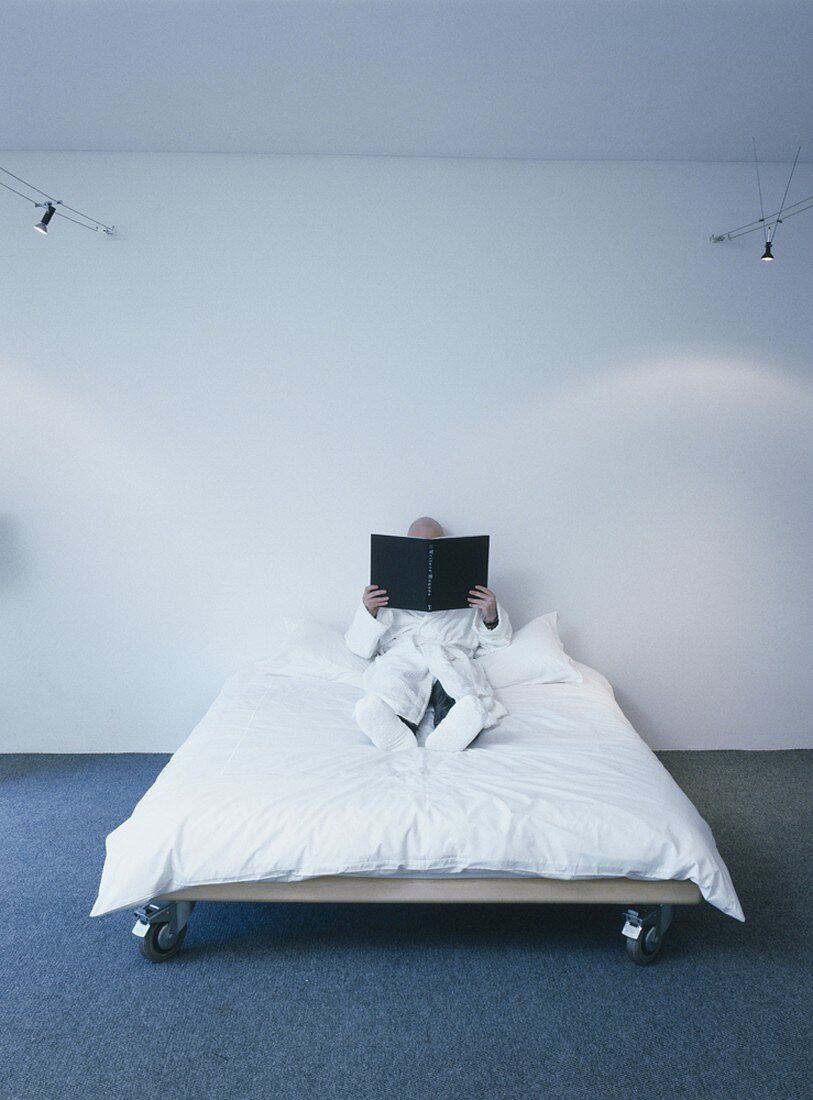 Steriles Schlafzimmer mit Doppelbett auf Rollen und ein Mann im Morgenmantel