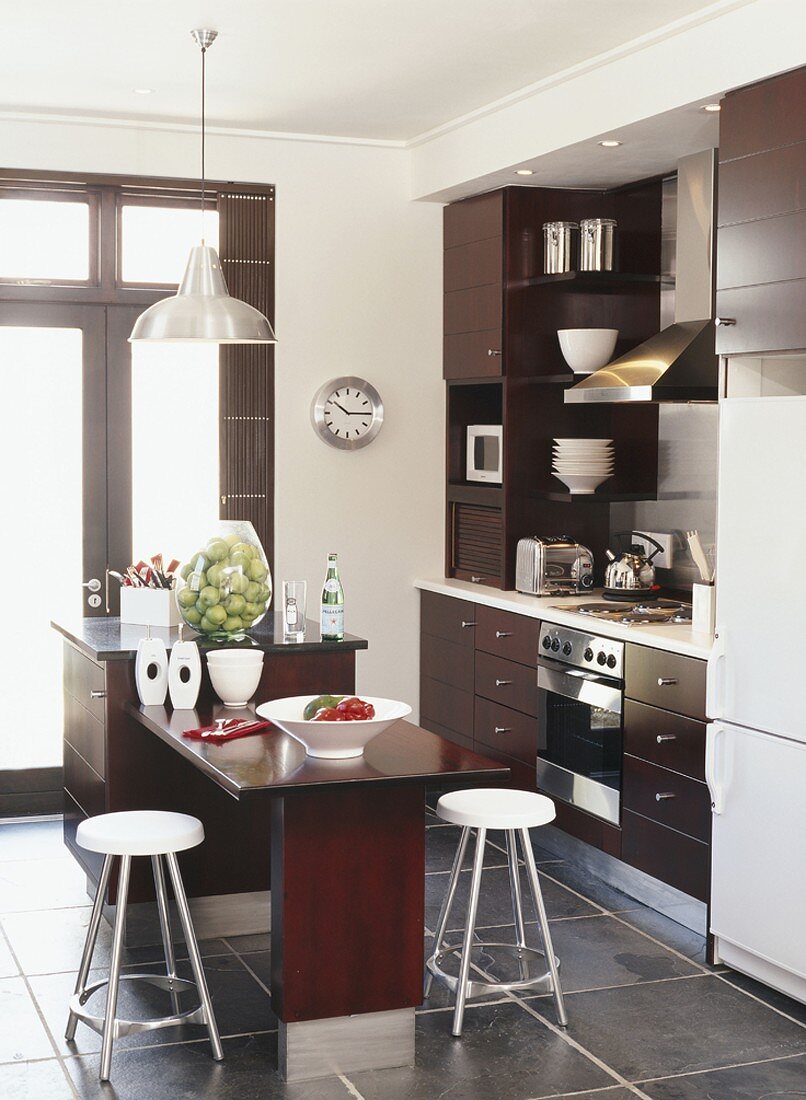 Küche mit dunkel braunen Küchenschränken und Kochinsel mit integriertem Esstisch