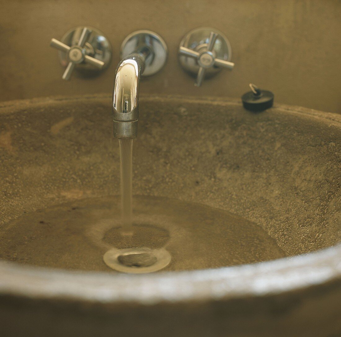 Ausschnitt eines runden Steinwaschbeckens mit fließendem Wasser