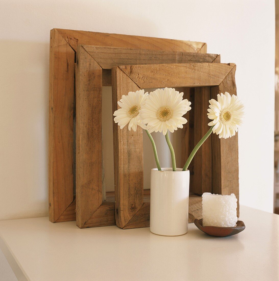 Three wooden picture frames and vase of gerbera daisies