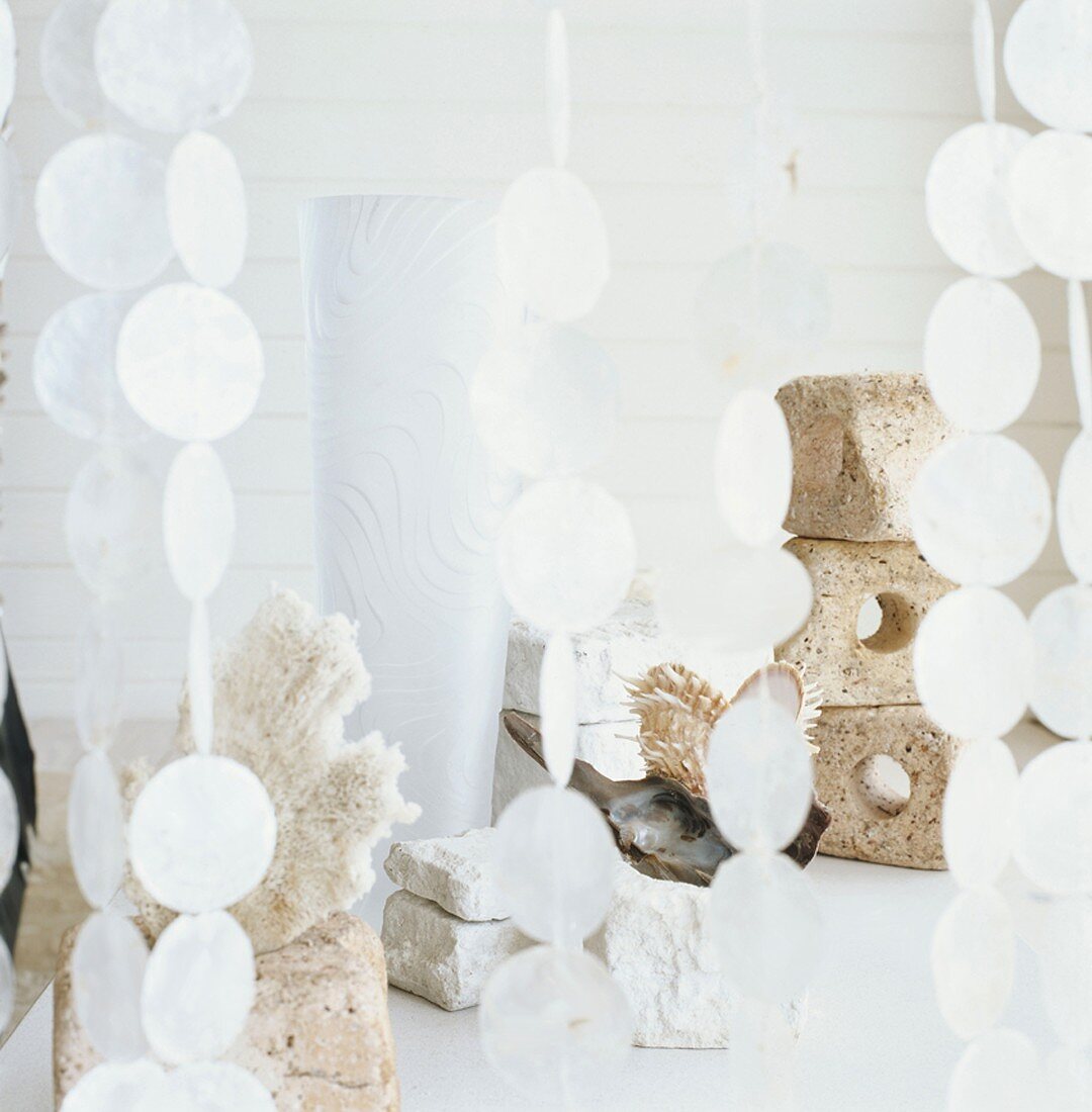 Gestapelte Steine und Dekorationsartikel hinter einem Pailletten-Vorhang