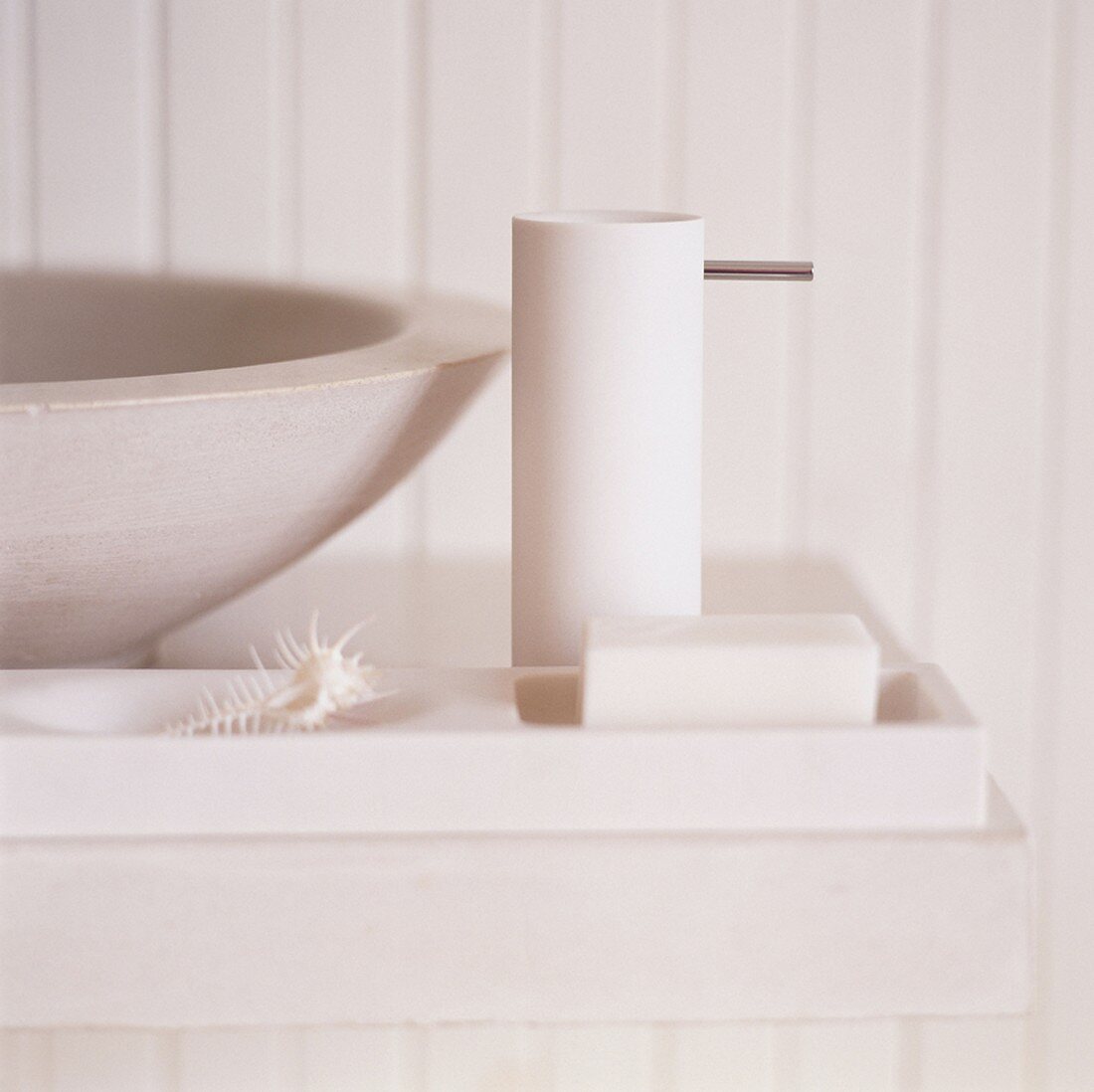 Ausschnitt eines Seifenspenders und einer Seife neben einem runden Waschbecken