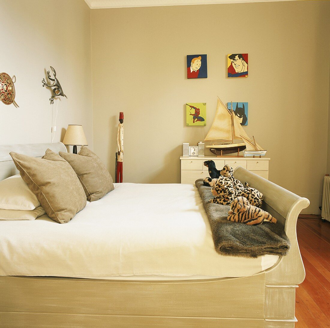 Doppelbett mit Stofftieren am Bettende und Comicfiguren an der Wand eines Schlafzimmers