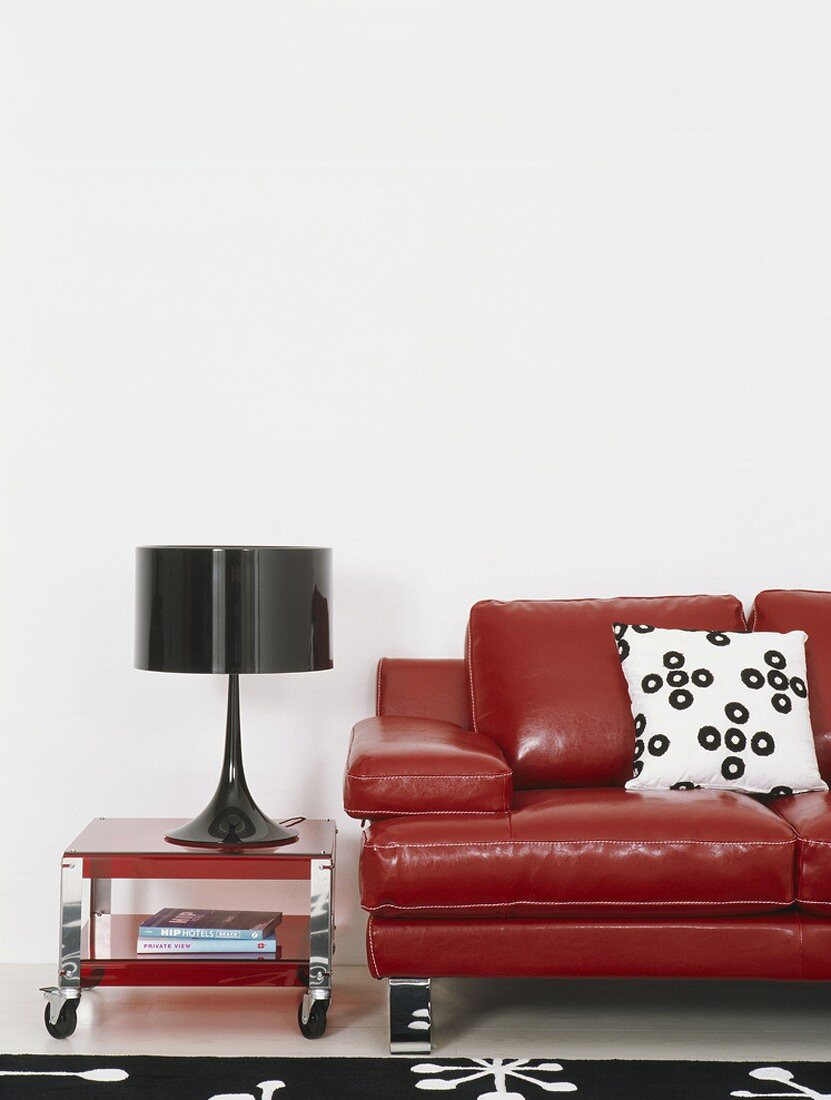 A red leather couch with black table lamp