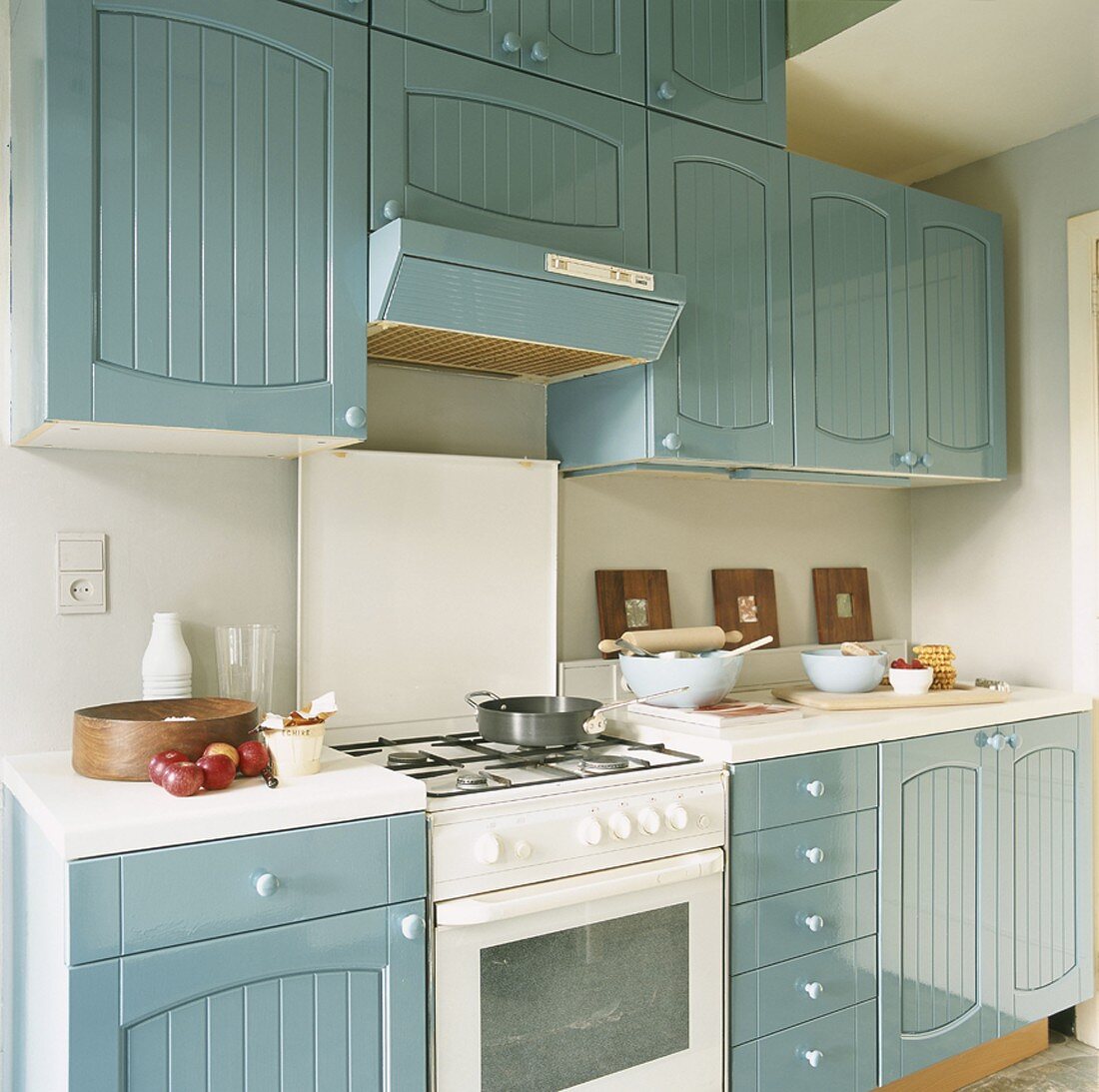 Eine Landhausküche mit blau-grauen Schrankfronten und einem Gasherd