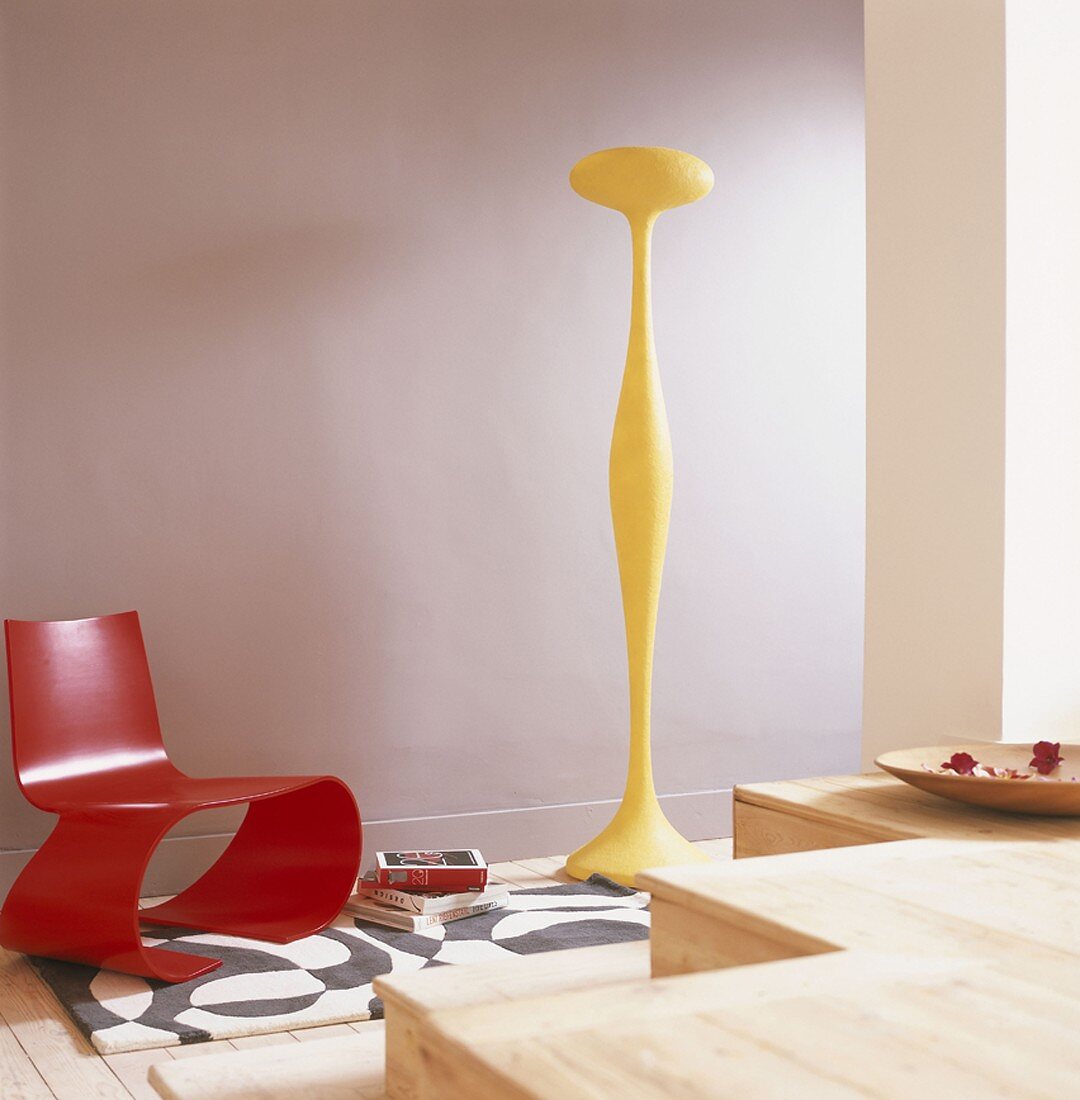 Designer-Möbelstücke in rot und gelb vor violetter Wand