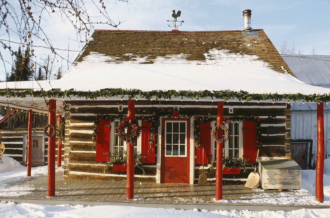 Verschneites und weihnachtlich dekoriertes Haus mit überdachter Veranda