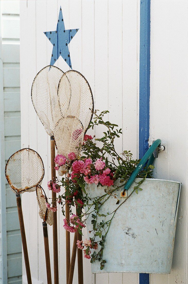 Kescher und Blumen an der Wand hängend