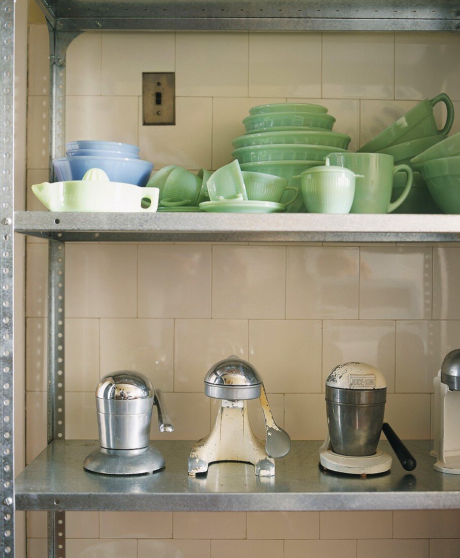 Metallregal mit Geschirr und anderen Küchenutensilien vor gefliester Wand