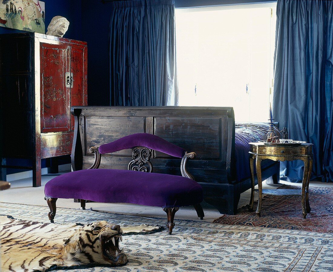 Schlafzimmer mit erlesenen Möbeln, schweren, blauen Fenstervorhängen, Seidenteppichen und einem Tigerfell mit -kopf