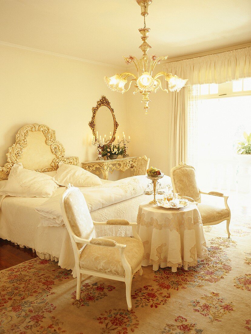 Opulentes Schlafzimmer mit prunkvollem Doppelbett und kleinem, runden Frühstückstisch mit Polsterstühlen