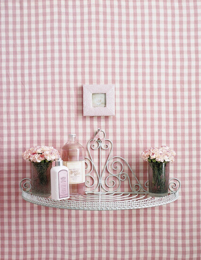 Ein kleines Regal an rosa-weiss-karierter Wand