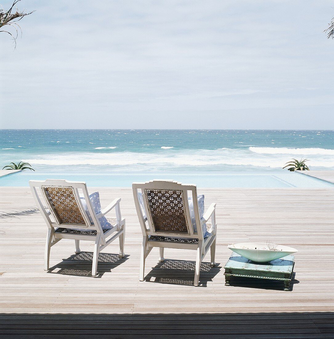 Zwei Stühle auf Terrasse am Meer