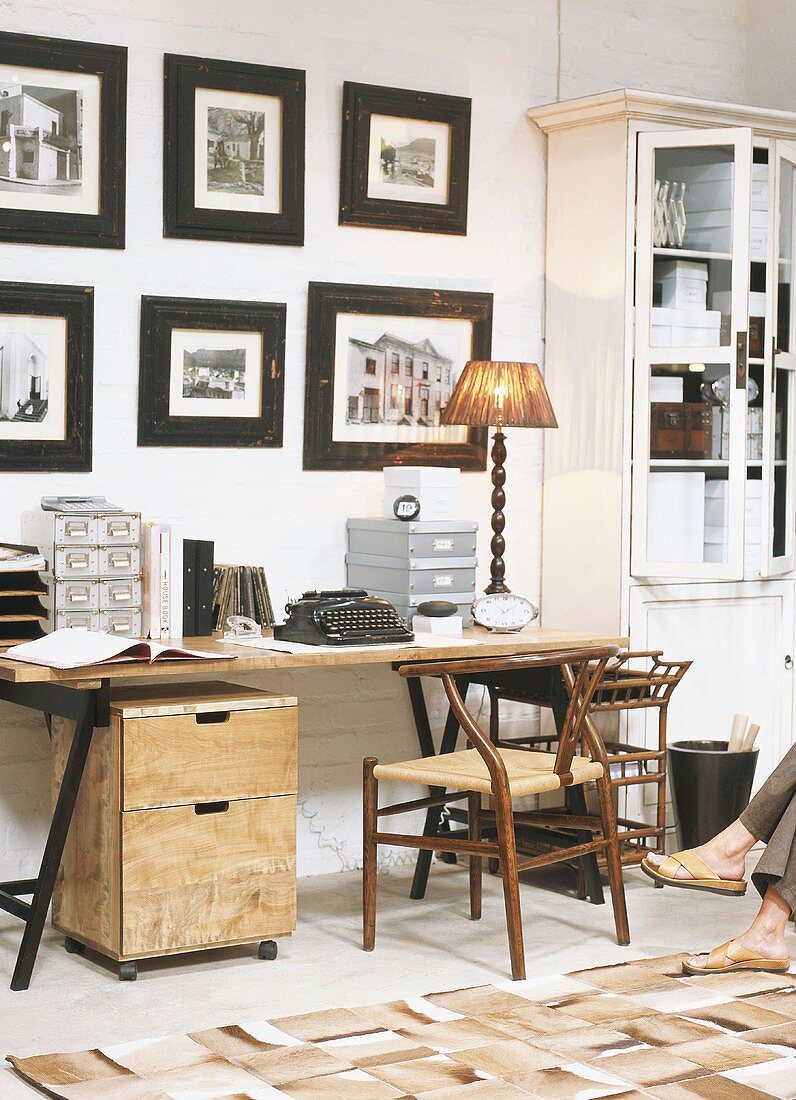 Arbeitsraum mit eingerahmte Bilder über Holzschreibtisch mit alter Schreibmaschine
