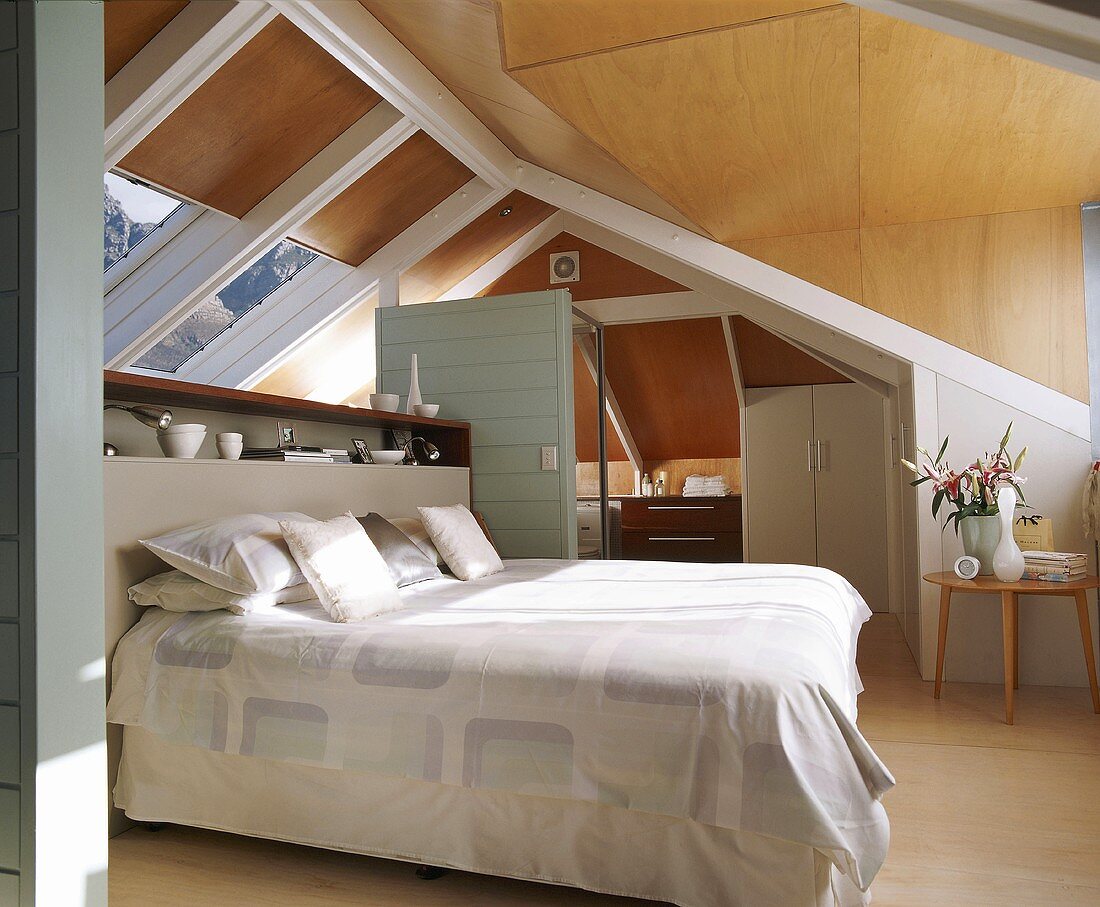 Doppelbett und Bad en suite unter Schrägdach mit großen Dachfenstern