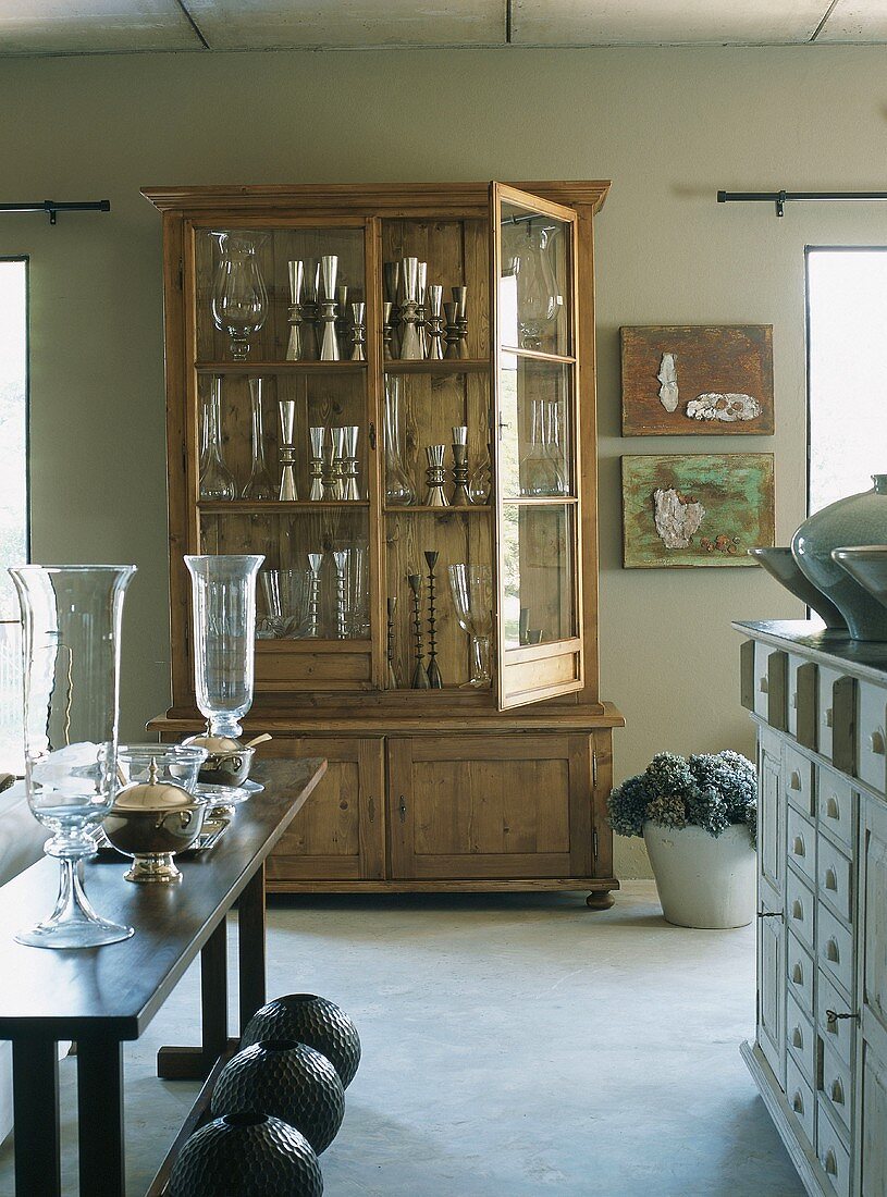 Ein geöffneter Vitrinenschrank mit Vasen und Kelchen aus Glas und Silber