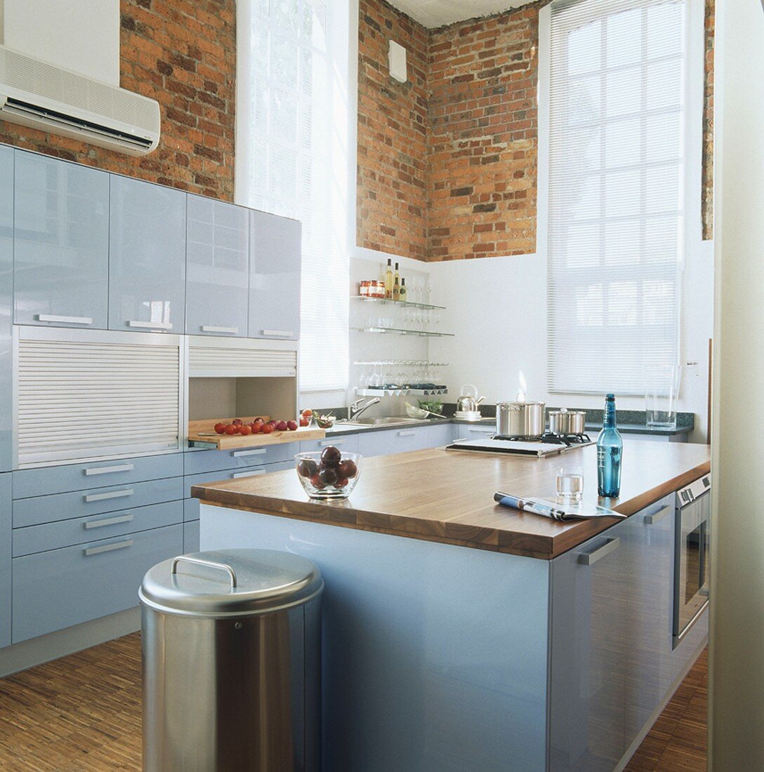 Moderne Küche mit hellblauen Hochglanzfronten und Backsteinwänden