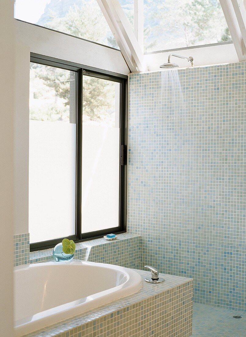 Offene Dusche und Badewanne mit blauen Mosaikfliesen und verglaster Dachkonstruktion