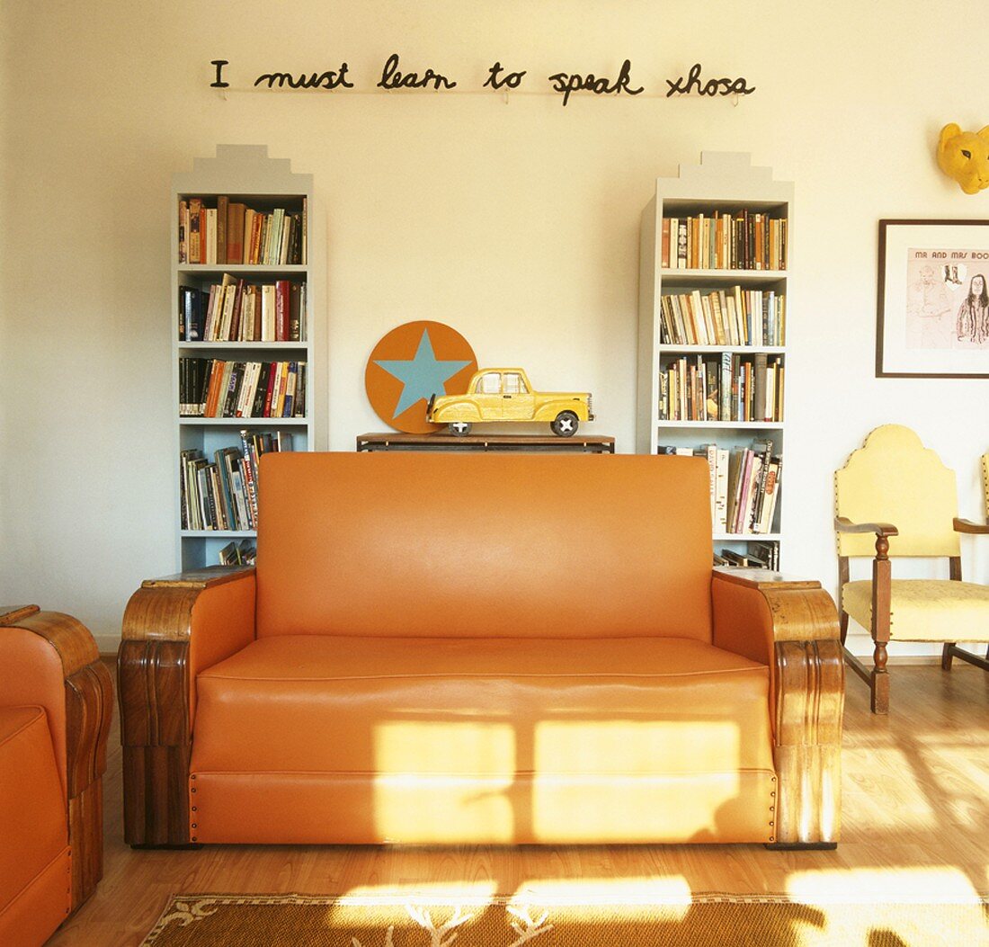 Wohnraum mit Sofas, Bücherregalen & Schriftzug an der Wand