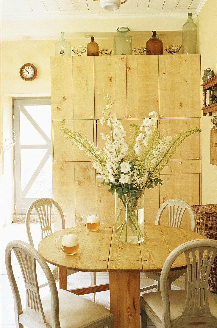 Zwei volle Biergläser auf einem runden Holztisch vor rustikalem Einbauschrank