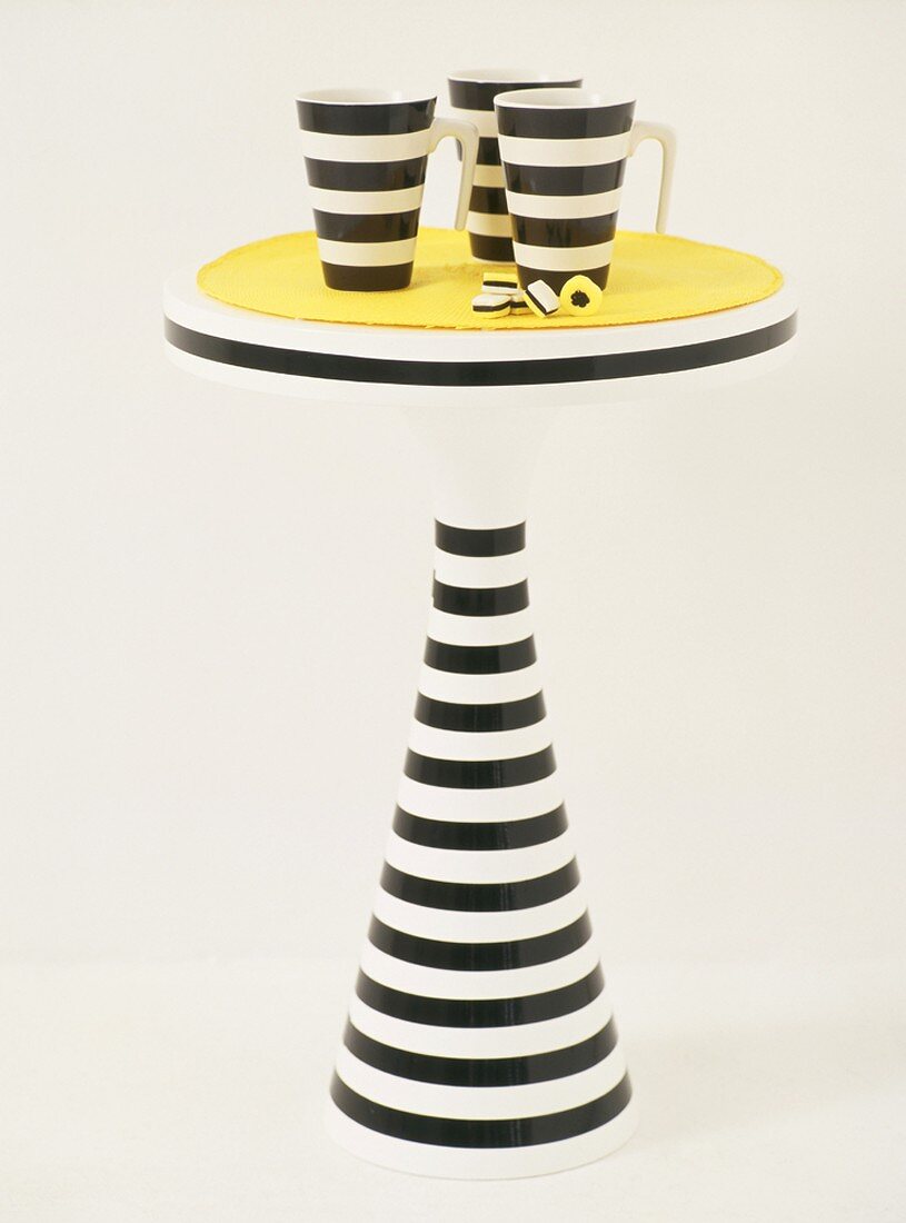 Black and white striped mugs on small table