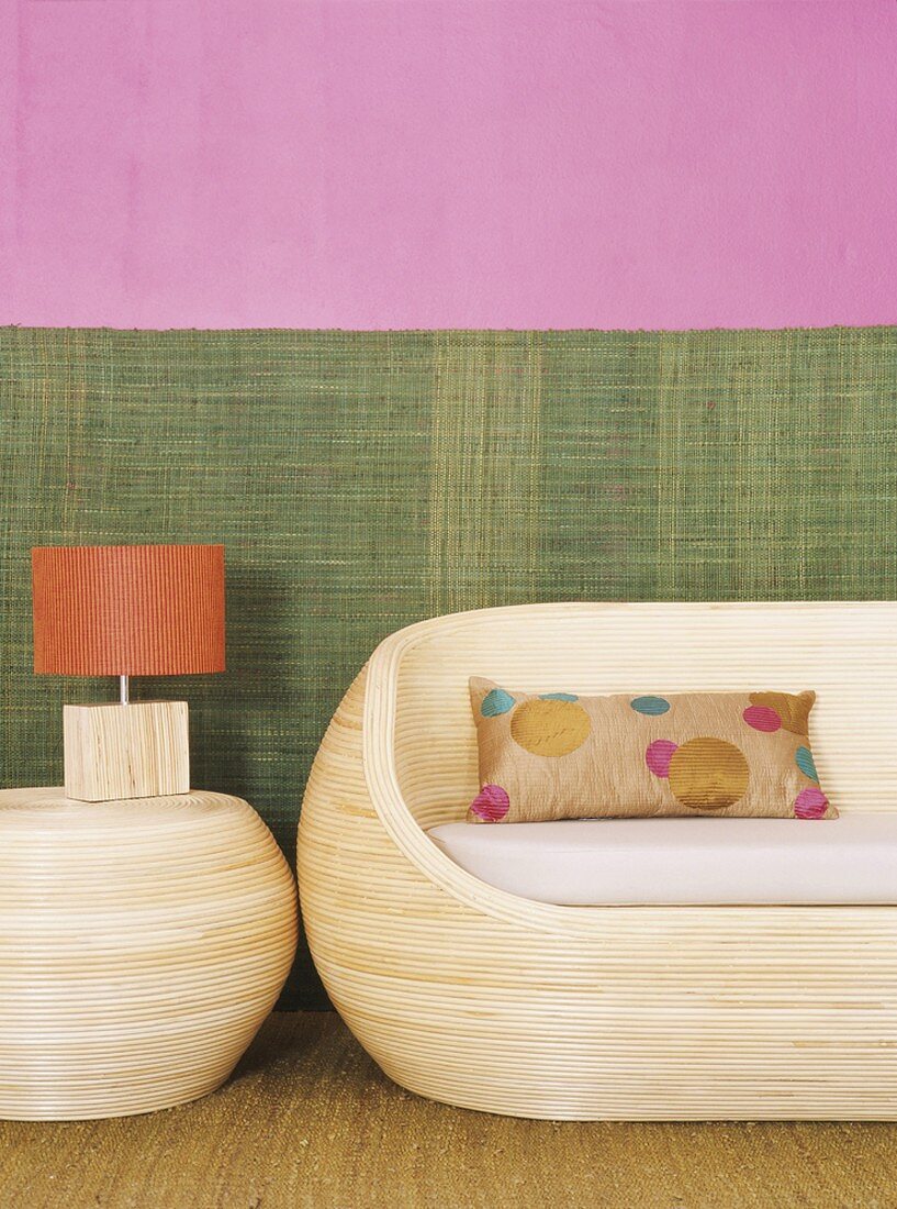 Wooden couch and table lamp against two-tone wall