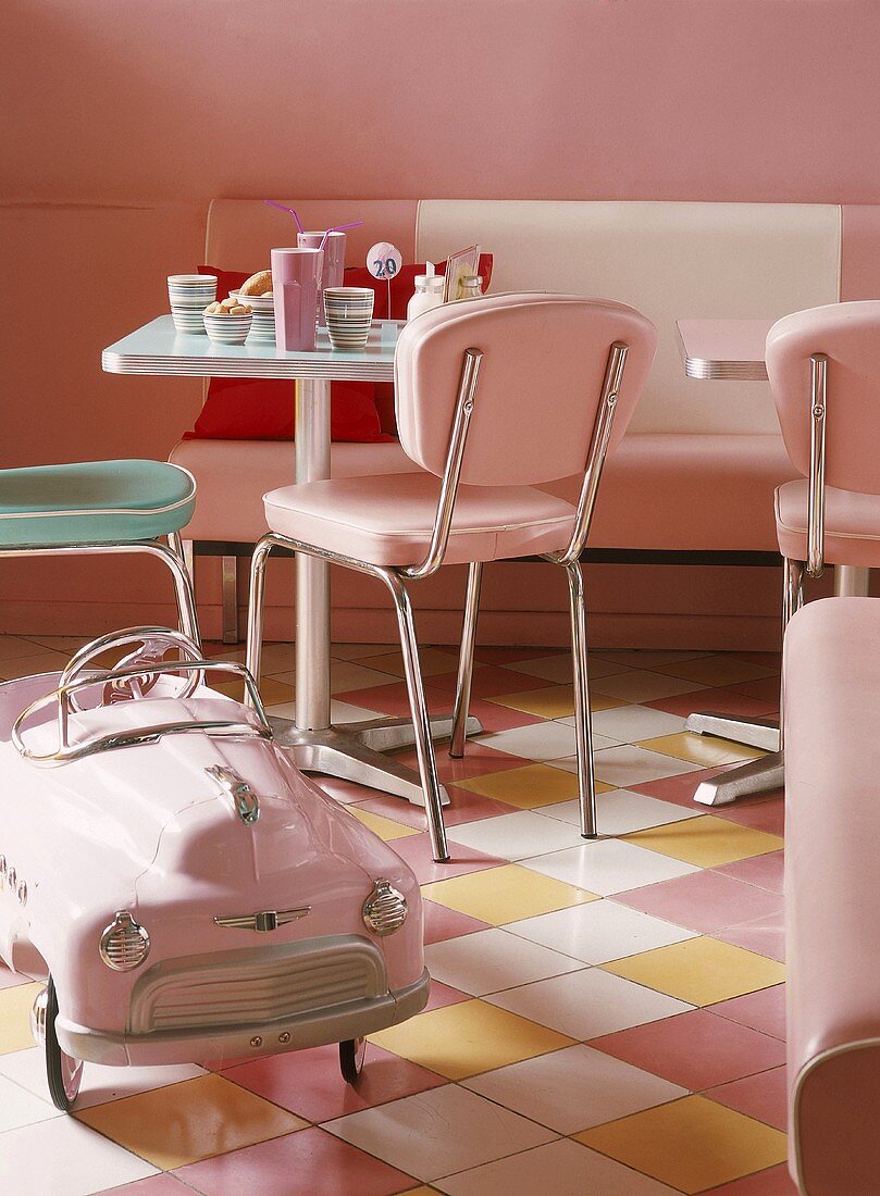 Quadratischer Tisch und rosa Spielzeugauto im Stil der 50iger Jahre in einem Diner
