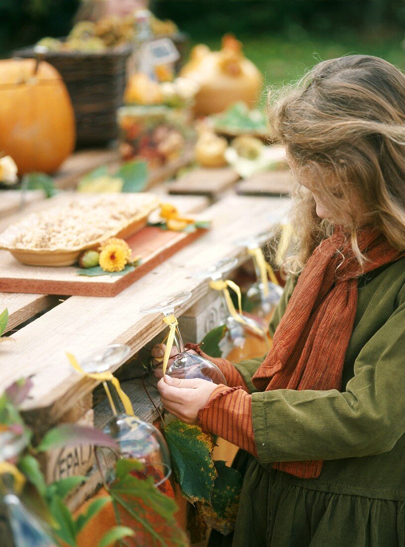 Mädchen an herbstlich dekoriertem Büffet im Freien