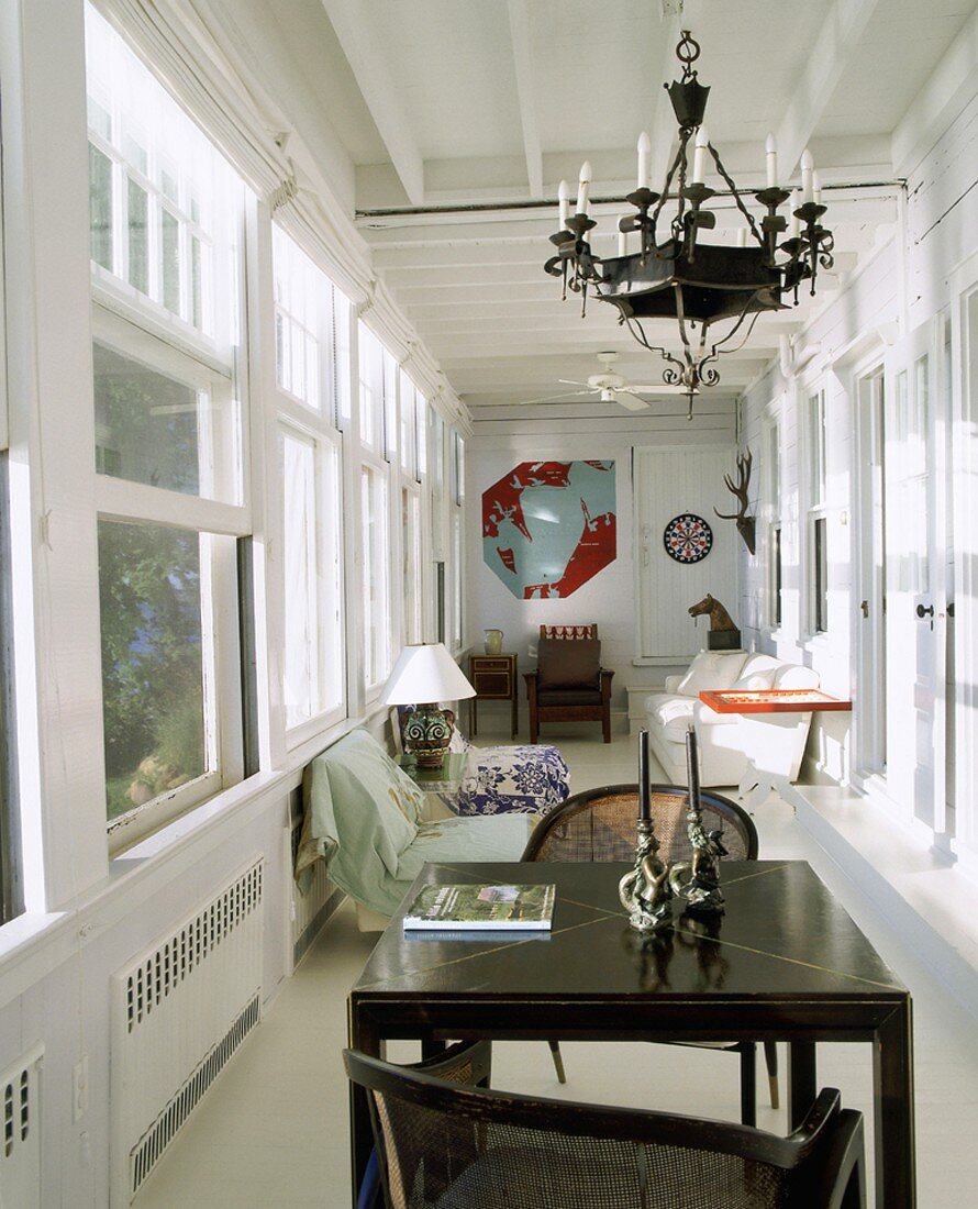 Schmales, helles Wohnzimmer mit einer langen Fensterfront und gemütlichen Polstermöbeln im Hintergrund
