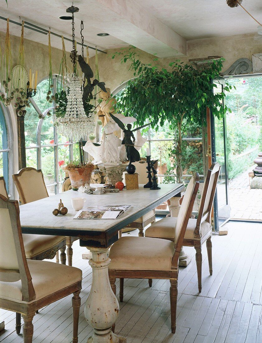 Dining table and antique, shabby-chic chairs in traditional conservatory