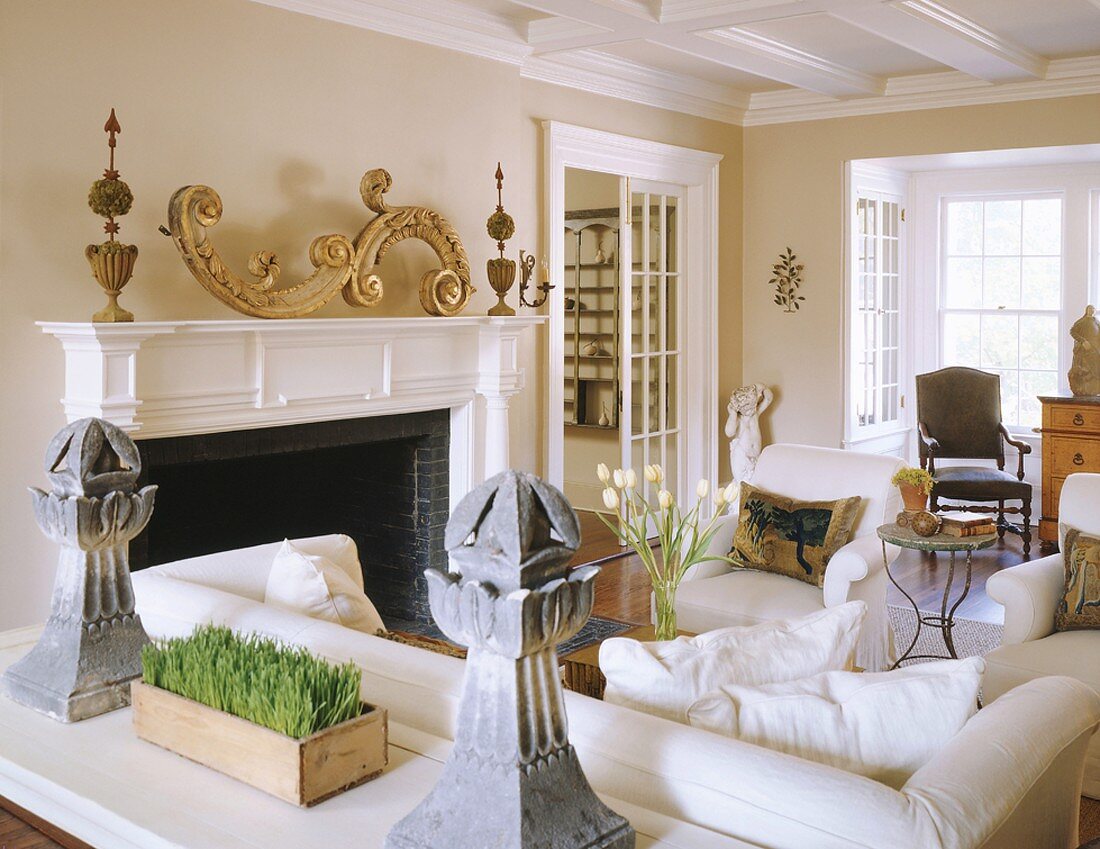 Behagliches Wohnzimmer mit offenem Kamin, weissen Polstermöbeln und einer weiss lackierten Holzdecke