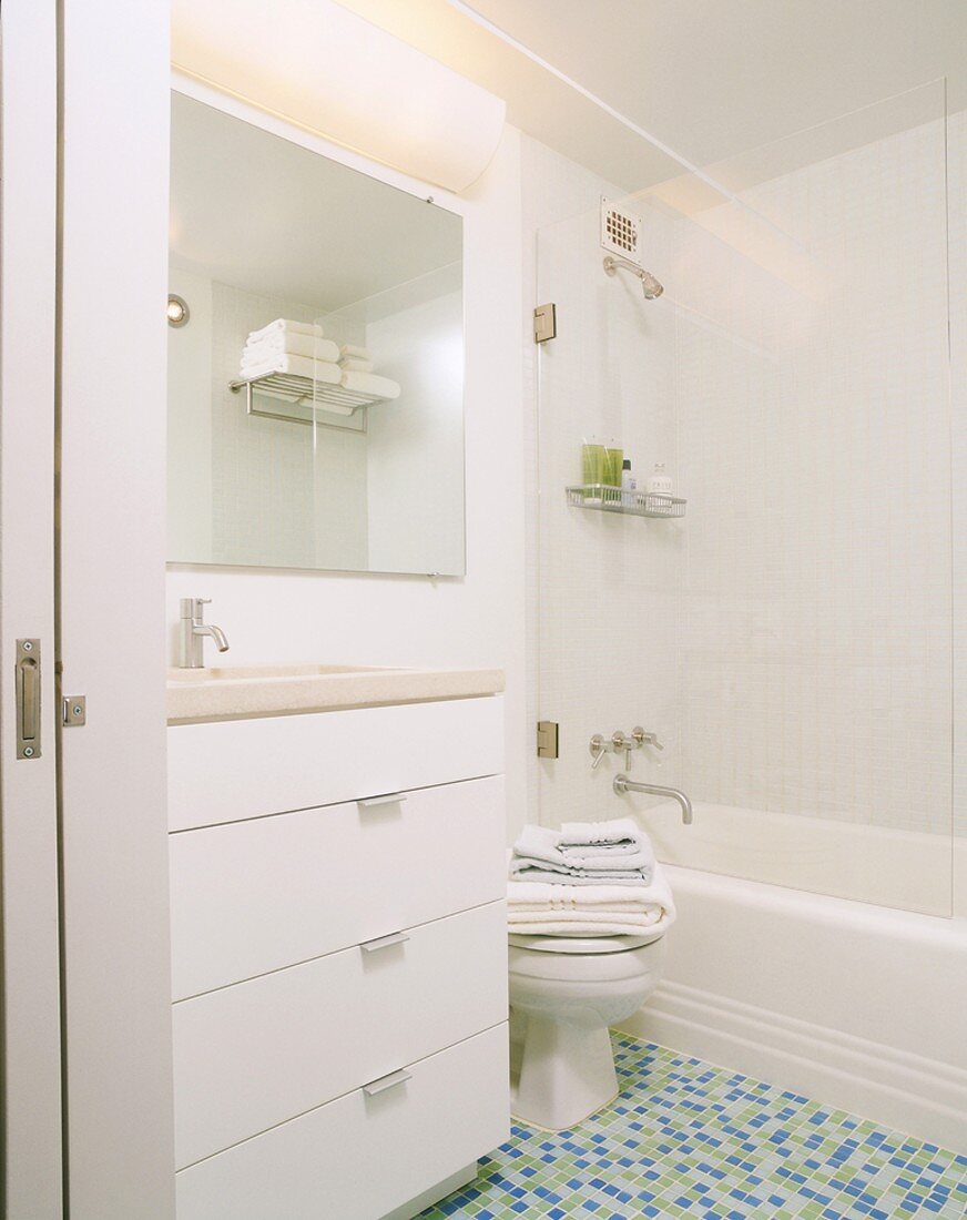 Helles Badezimmer in Weiß mit Toilette und einem Mosaikfliesenboden