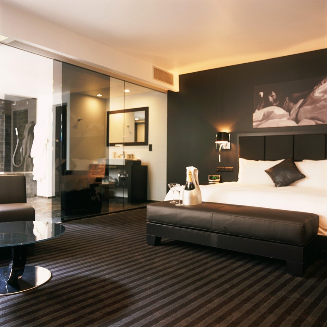 Luxuriöses, schwarz-weisses Schlafzimmer mit gepolsteter Ledersitzbank und Badezimmer en suite