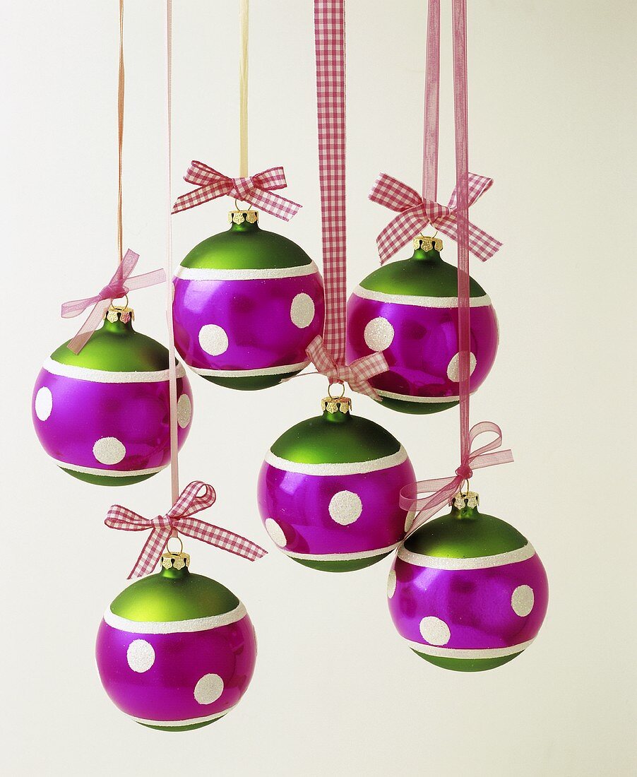 Several colourful Christmas baubles hanging on ribbons