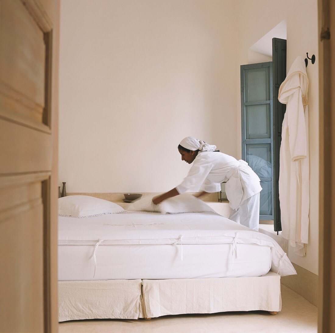 Zimmermädchen macht Bett im Hotel