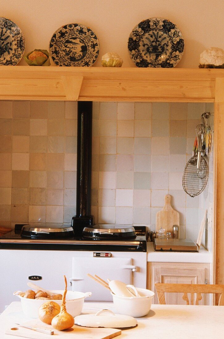 Küche mit Holzofen, darüber Holzregal mit Porzellantellern