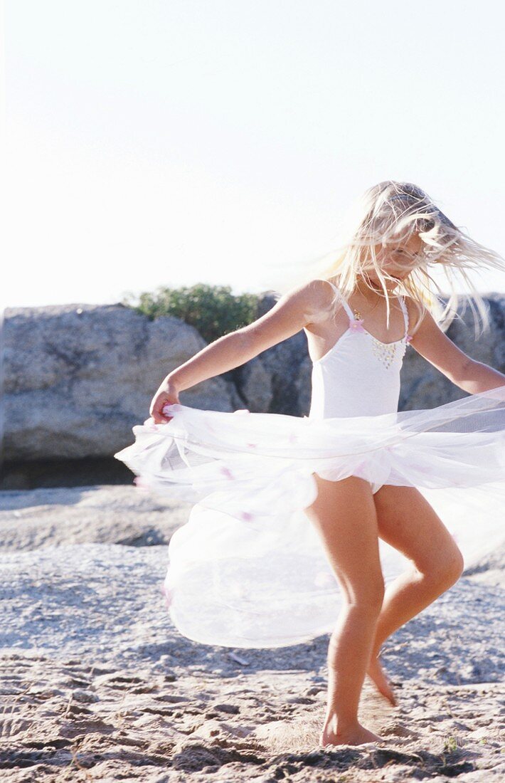 Mädchen mit Kleid tanzt am Strand