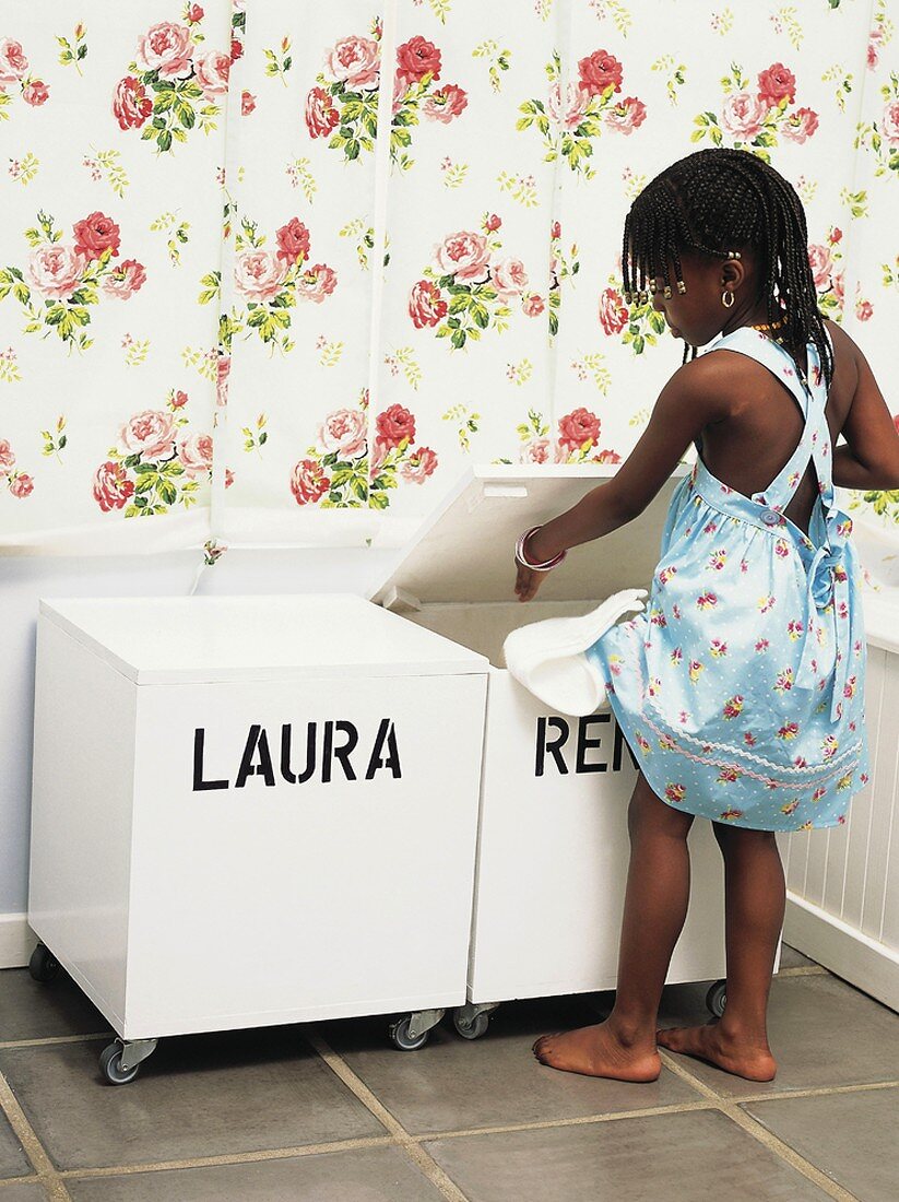 Kleines Mädchen räumt Spielsachen in eine Box