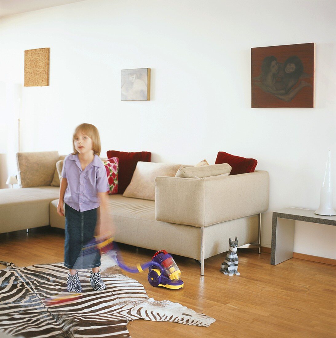 Mädchen spielt mit einem Kinder-Staubsauger im Wohnzimmer
