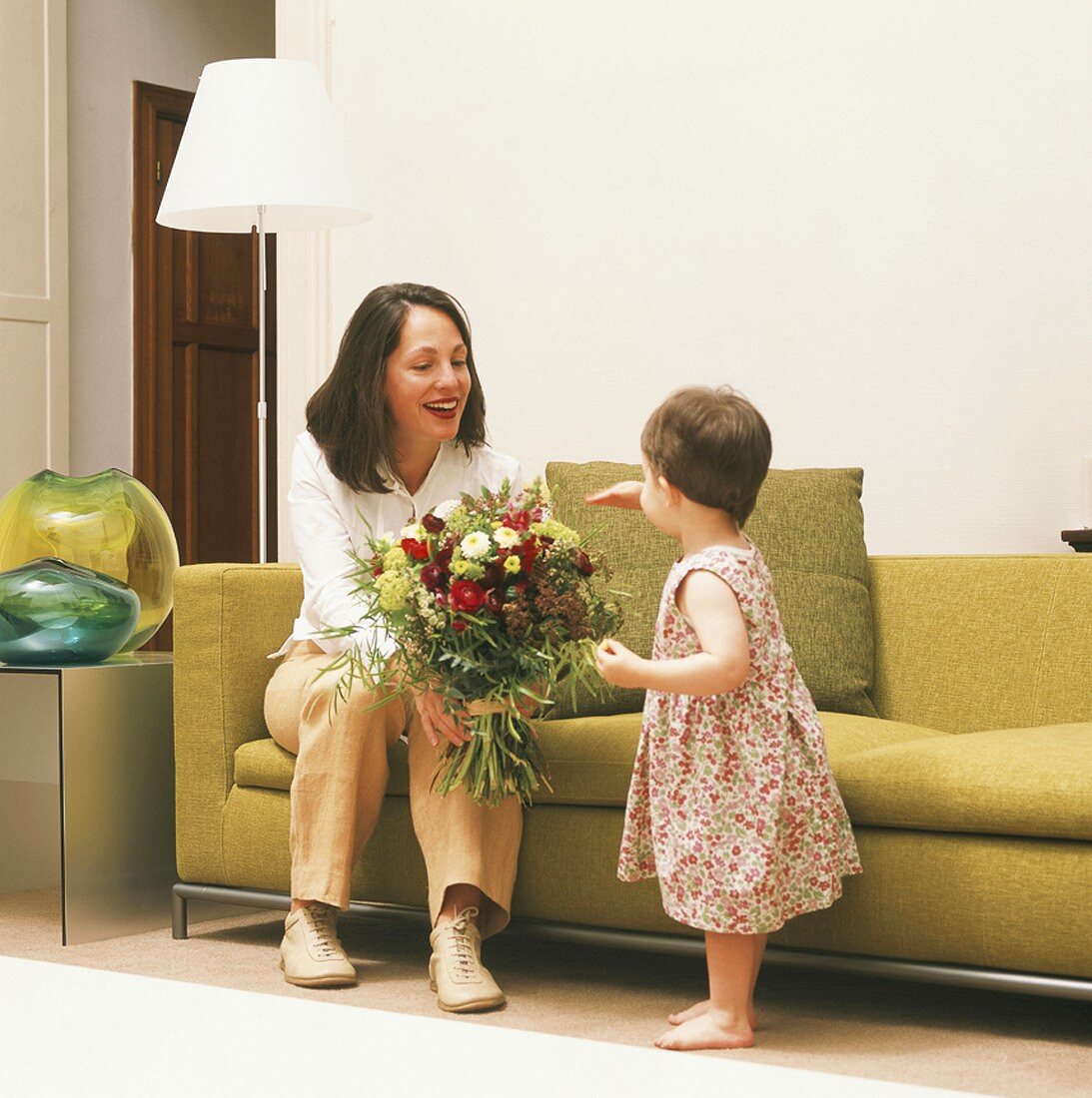 Mutter und Kind mit einem Blumenstrauss im Wohnzimmer